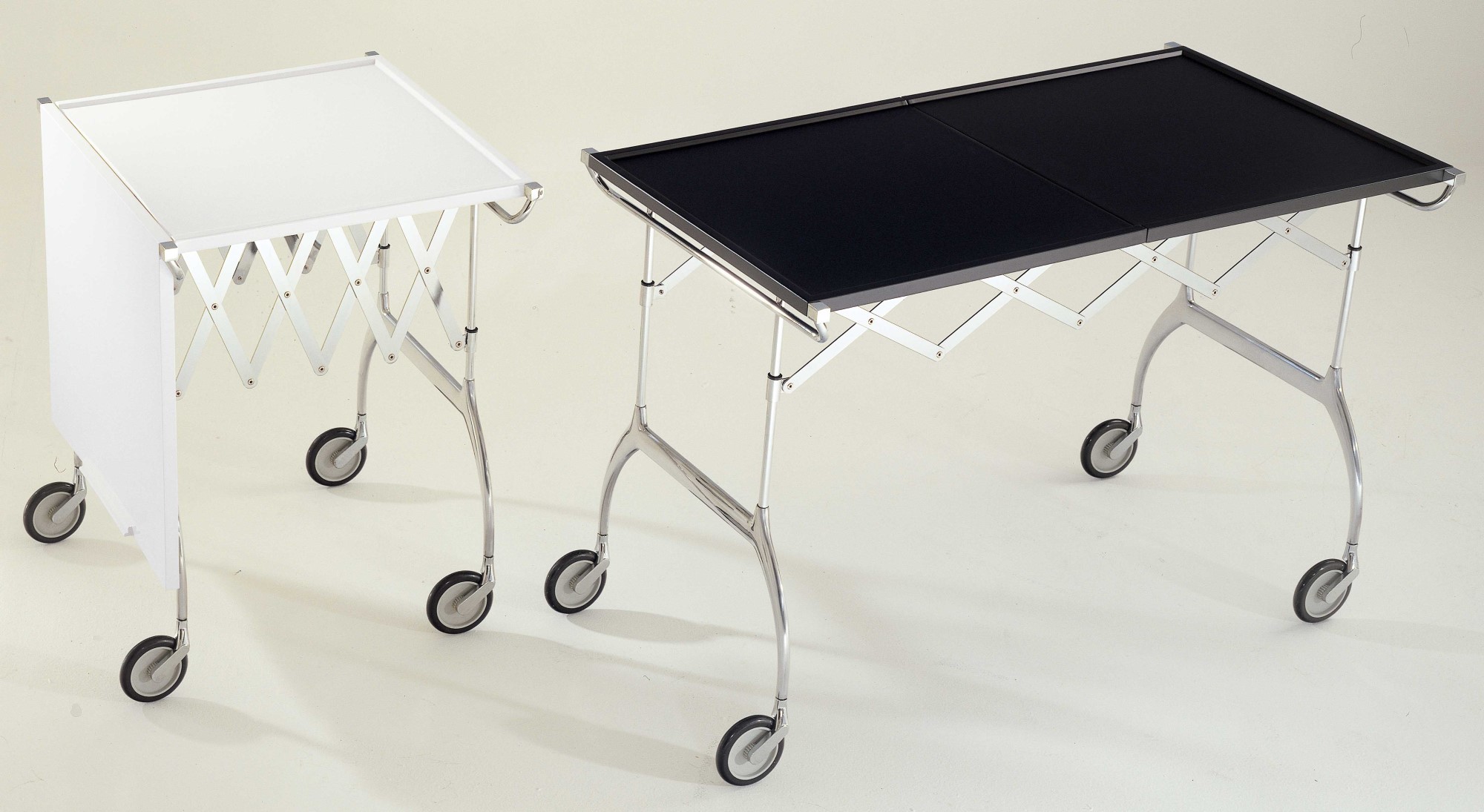 Schwarzer Kartell Battista Rollwagen neben weißem Modell, ausklappbarer Servierwagen mit Rollen.