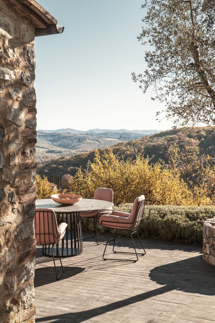 BC 07 Basket Outdoor Tisch von Janua mit Stühlen auf einer Terrasse mit Ausblick.