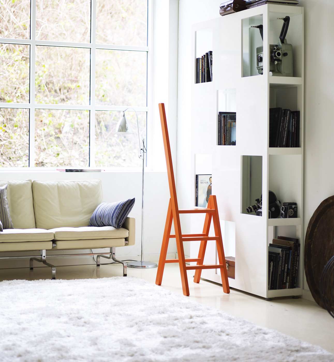 Orangefarbene Hindevadgaard Trittleiter aus Holz im modernen Wohnzimmer, ideal als Steighilfe und Dekoration.