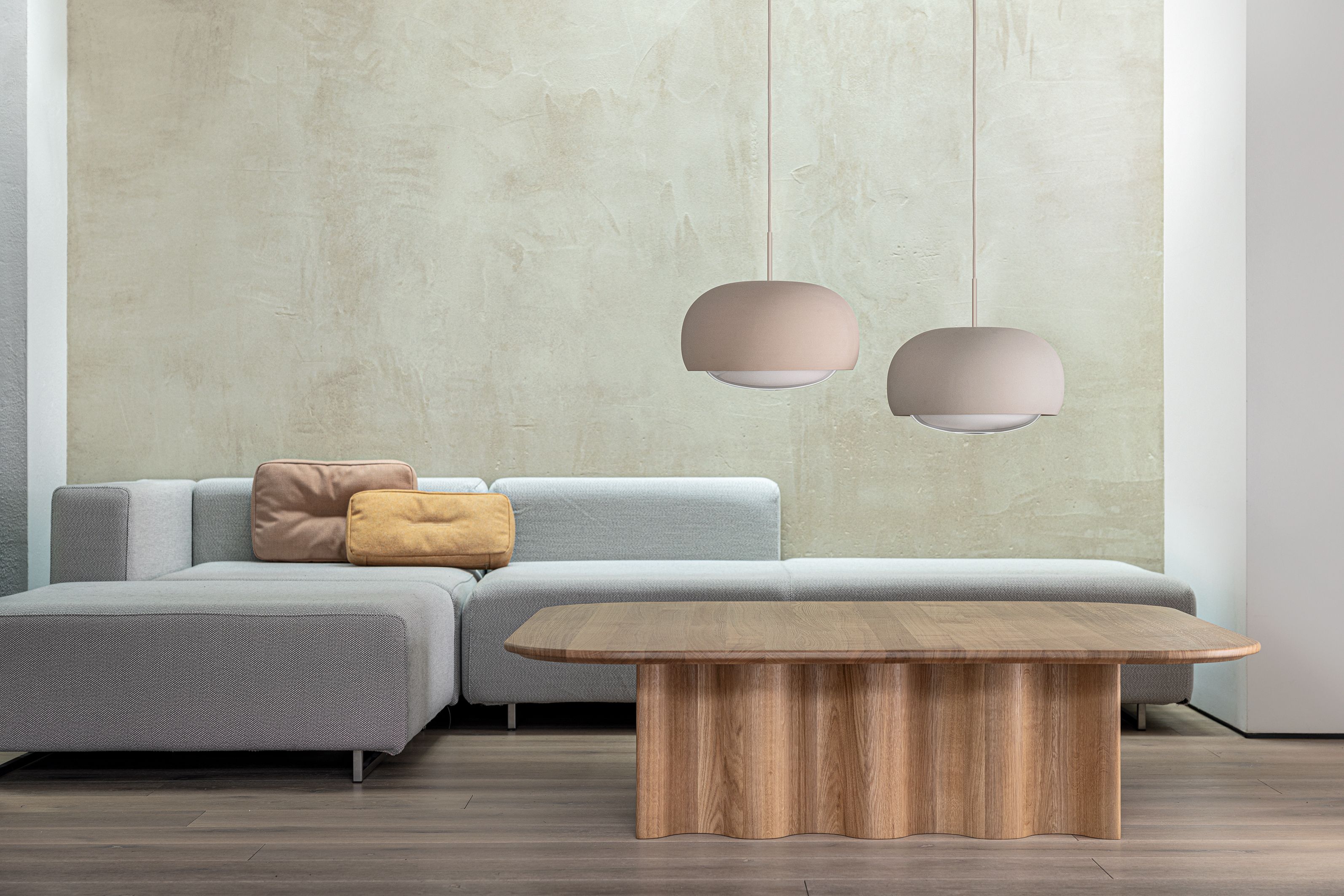 Rechteckiger Couchtisch "Curtain" aus massiver Eiche im Wohnzimmer mit Sofa und Pendelleuchten.