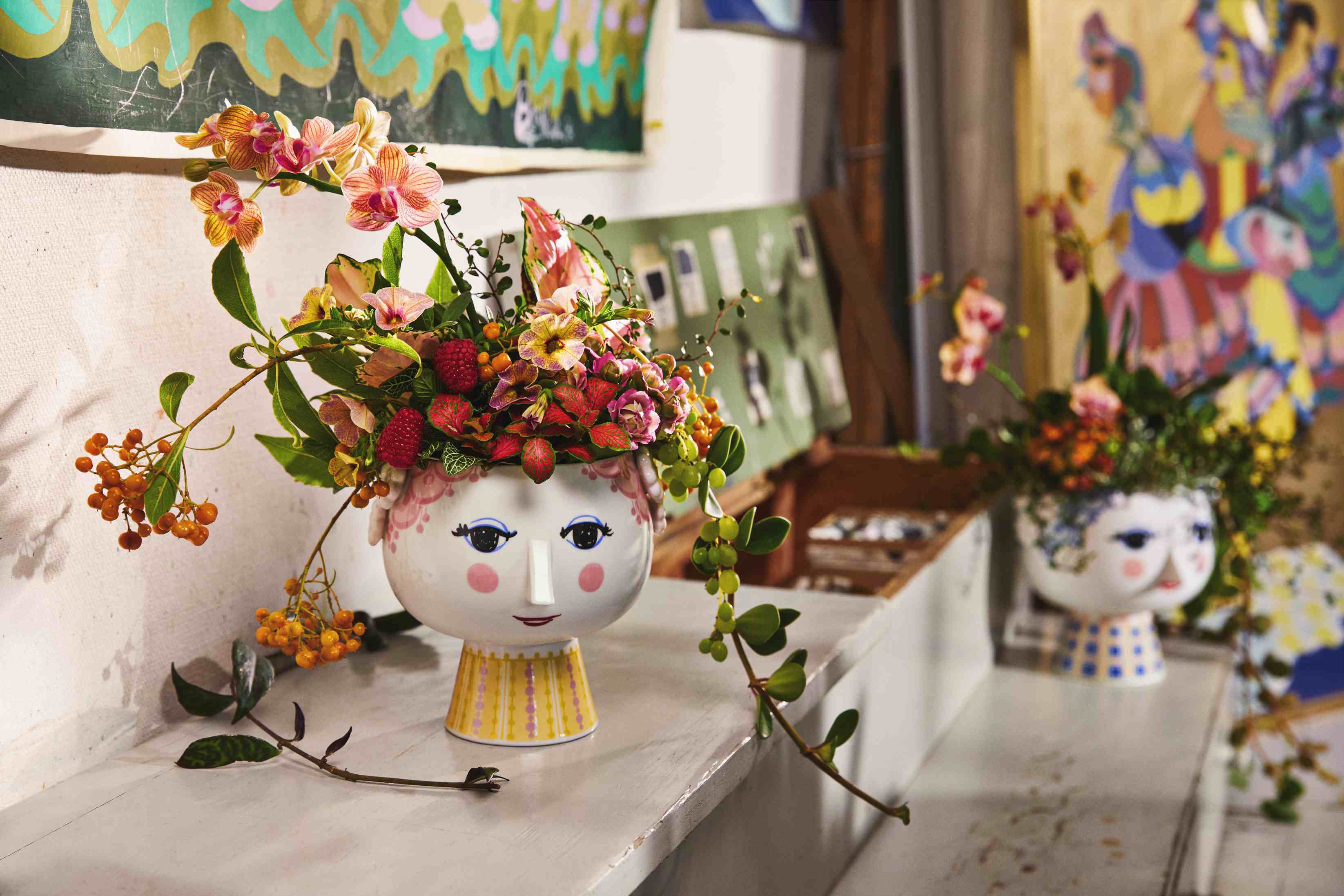 Nahaufnahme einer Keramikvase in Form eines Frauenkopfes mit Blumenarrangement, dekorative Wohnaccessoires.