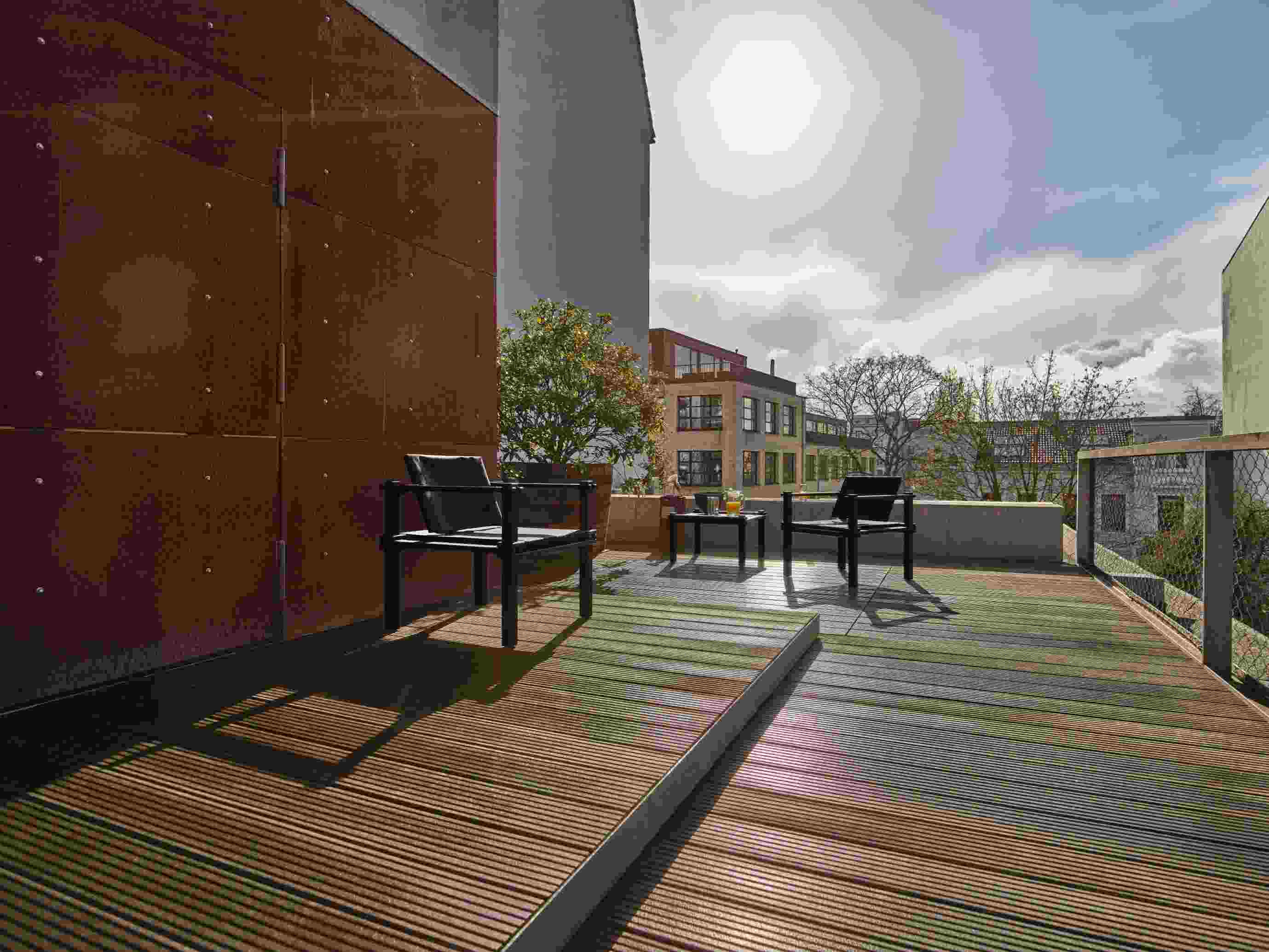 Zwei Farmer Sessel Outdoor Cor auf einer modernen Terrasse mit Holzboden und Blick auf die Stadt.