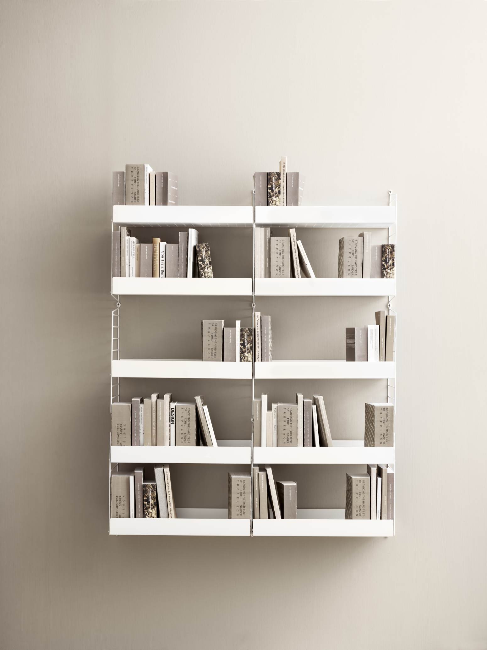 Weißes String Regalsystem mit Büchern an einer Wand, modernes Wandregal für Wohnzimmer.