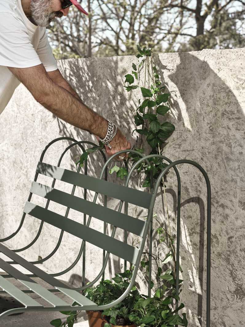 Gardener's Sofa von Design House Stockholm im Garten mit Efeu und Person.