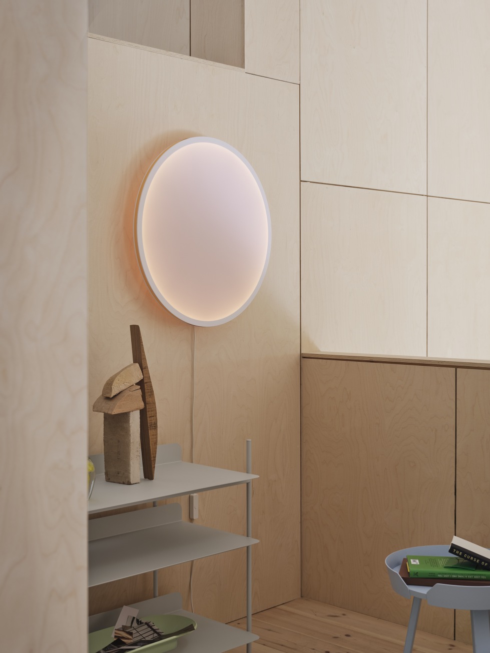 Helle, runde Muuto Wandleuchte "Calm Wall Lamp" an einer Holzwand, modernes Design.