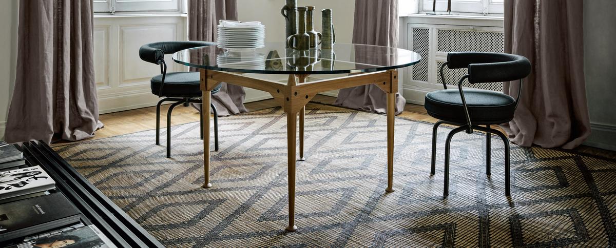 Esszimmer mit rundem Glastisch und zwei Cassina 7 Fauteuil Tournant Drehsesseln mit schwarzem Bezug.
