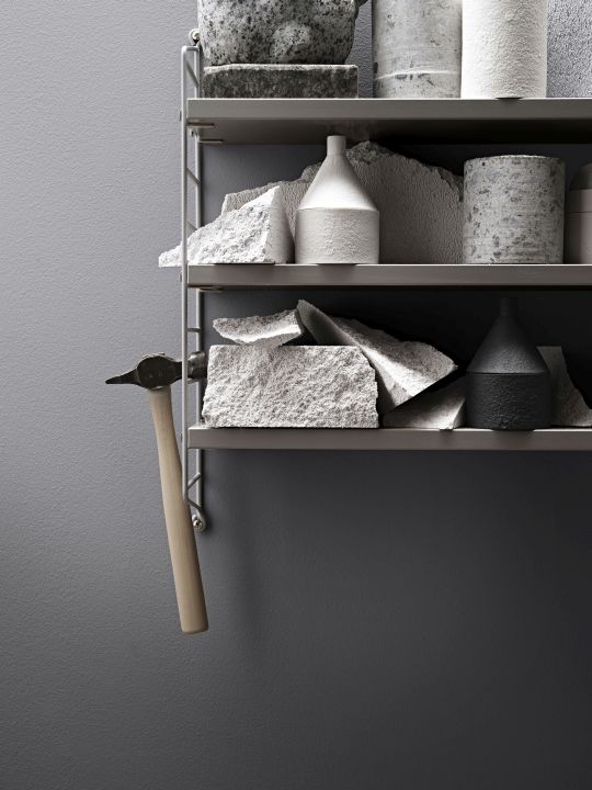 Nahaufnahme eines String Pocket Regals mit Dekorationsgegenständen und einem Hammer.
