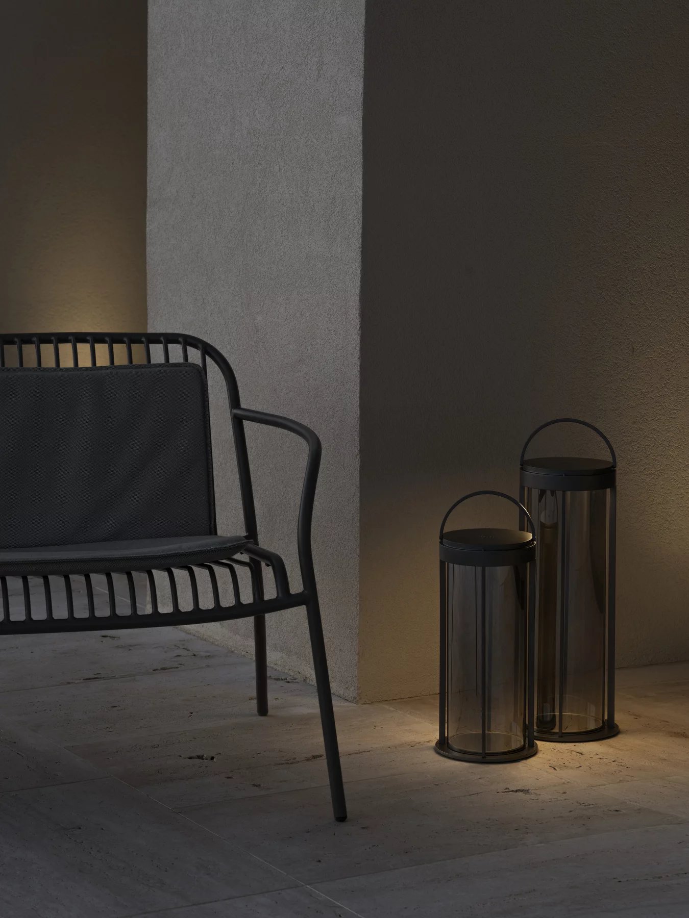 Blomus Yua Armlehnstuhl in Silk Gray mit Outdoor-Laternen für stimmungsvolle Gartenbeleuchtung und stilvolles Outdoor-Ambiente.