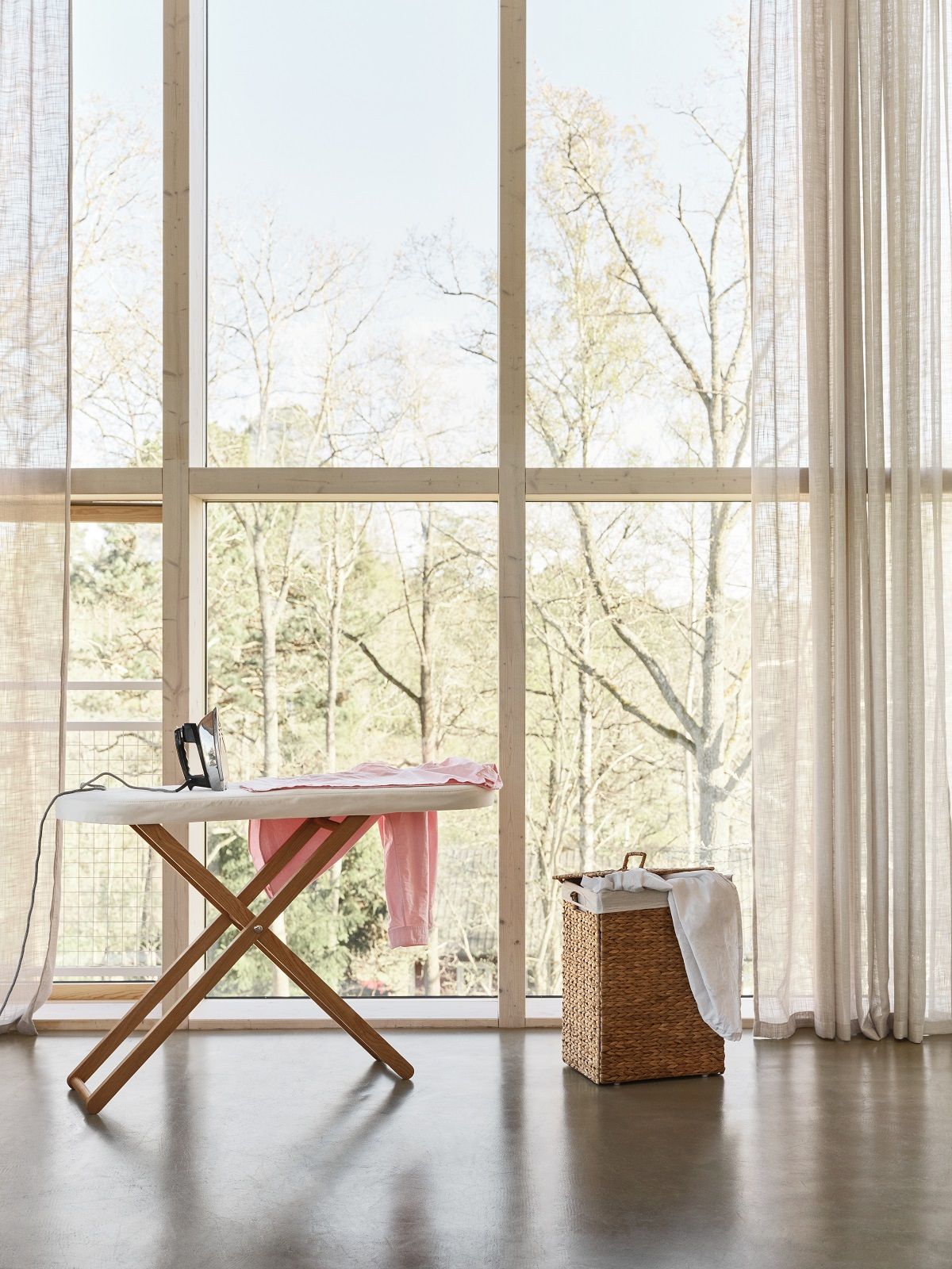 Cinderella Table Bügeltisch von Design House Stockholm mit Bügeleisen und Wäschekorb vor Fenster.