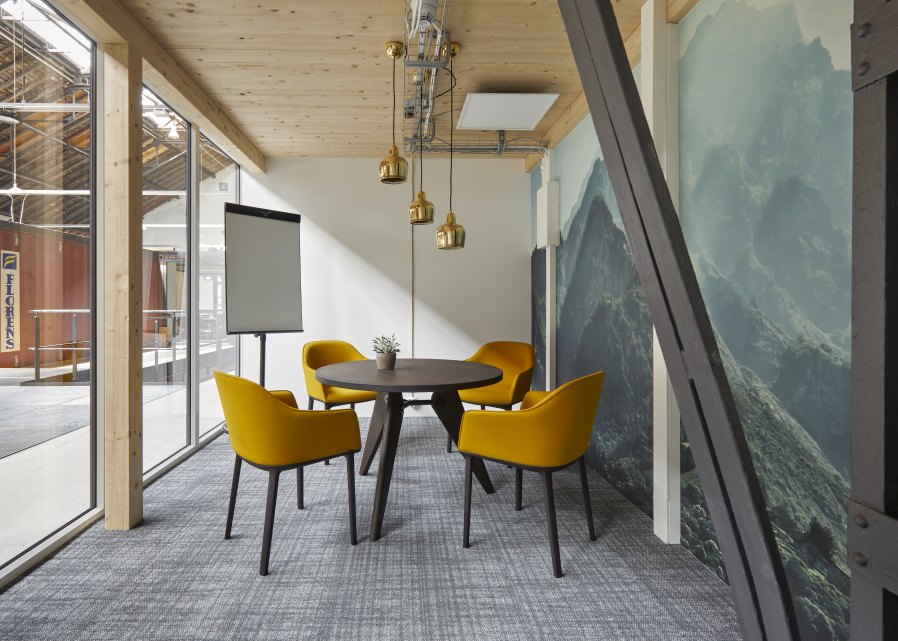 Besprechungsraum mit Vitra Gueridon Tisch, runder Tischplatte und vier gelben Stühlen für moderne Büroeinrichtung.