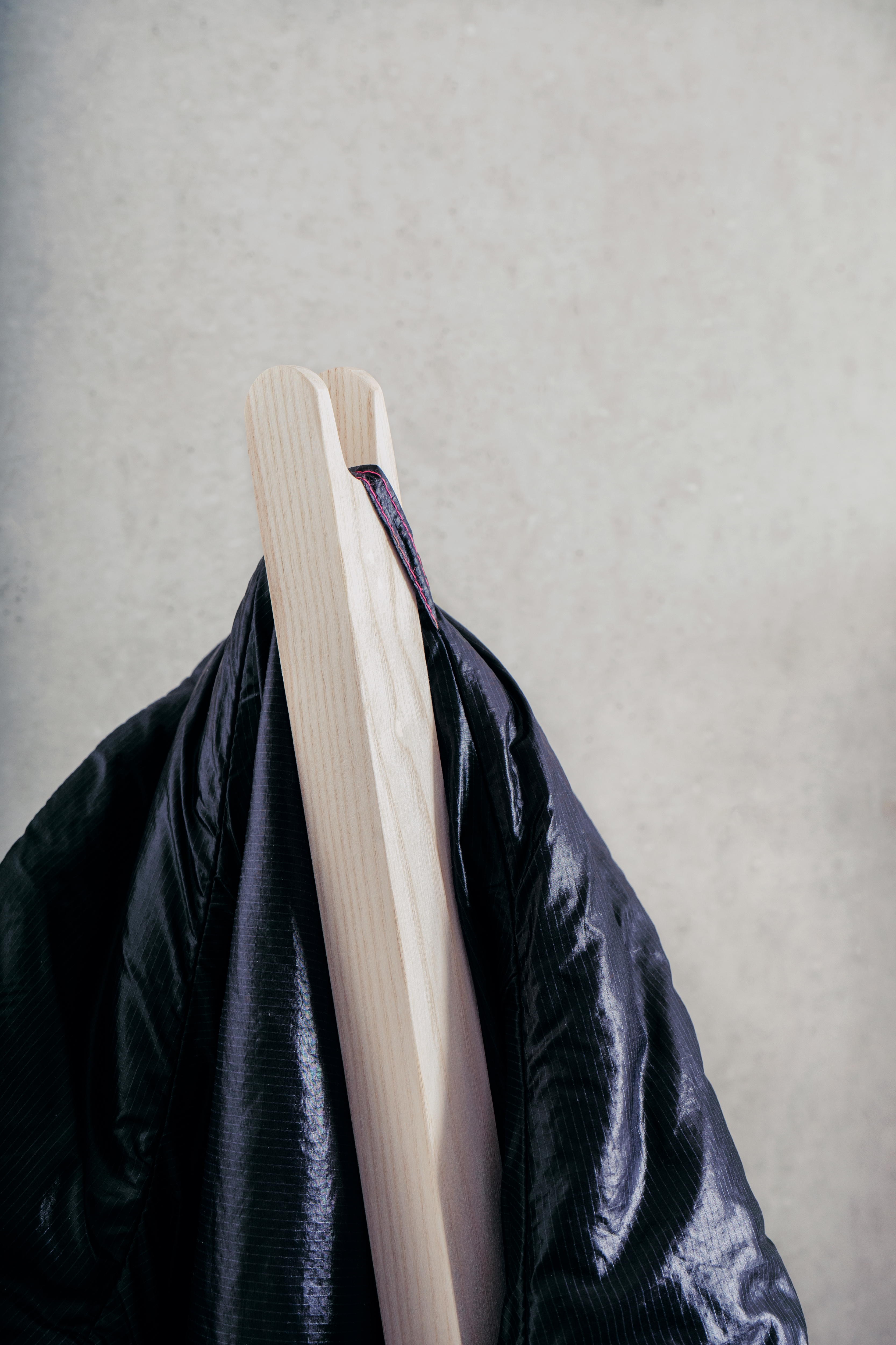 Nils Holger Moormann Pin Coat Garderobe mit Jacke aus leichtem, dunklem Stoff.