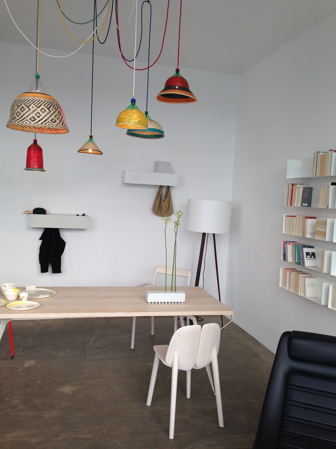 Helle Inneneinrichtung mit Müller Möbelwerkstätten CR Linea1 Wandgarderobe, Esstisch, Stühlen, Bücherregal und bunten Lampen.