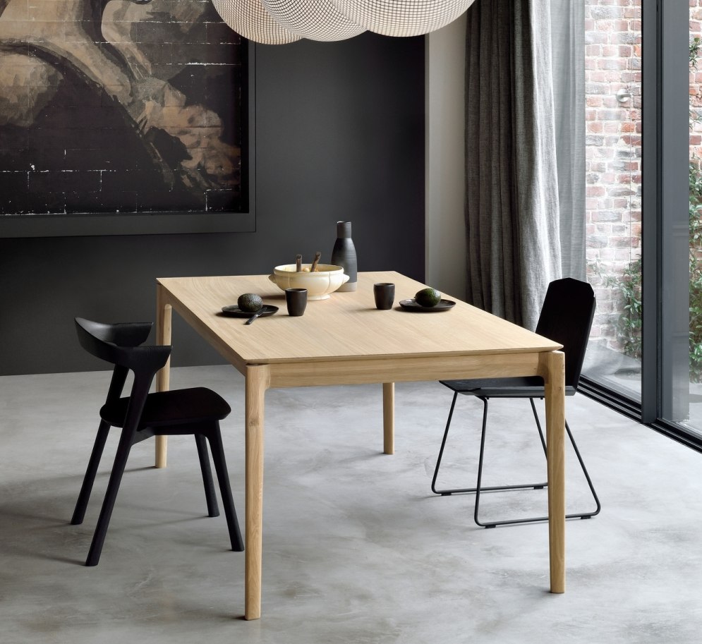 Heller Esstisch aus Holz mit zwei schwarzen Stühlen in modernem Esszimmer.