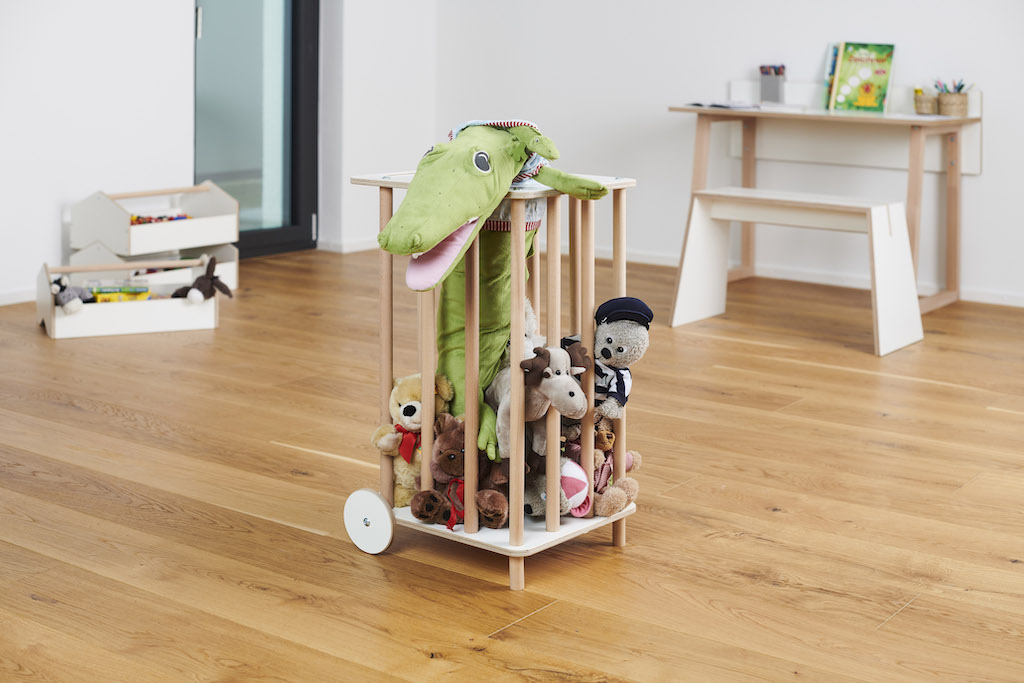 Tojo Kids Zoo Plüschtierkarren gefüllt mit Kuscheltieren, darunter ein grüner Krokodil, im Kinderzimmer auf Parkettboden.