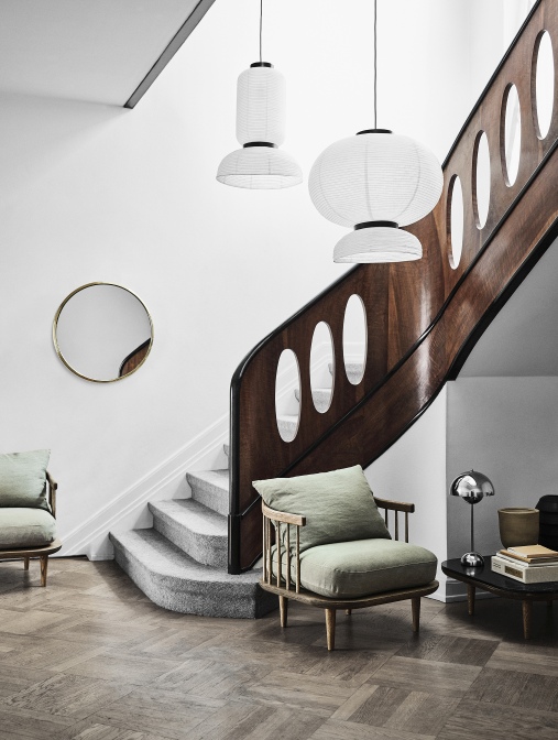 Innenaufnahme eines Wohnraums mit Fly Table Couchtisch, Sesseln, Treppe und dekorativen Lampen für stilvolles Wohnen.
