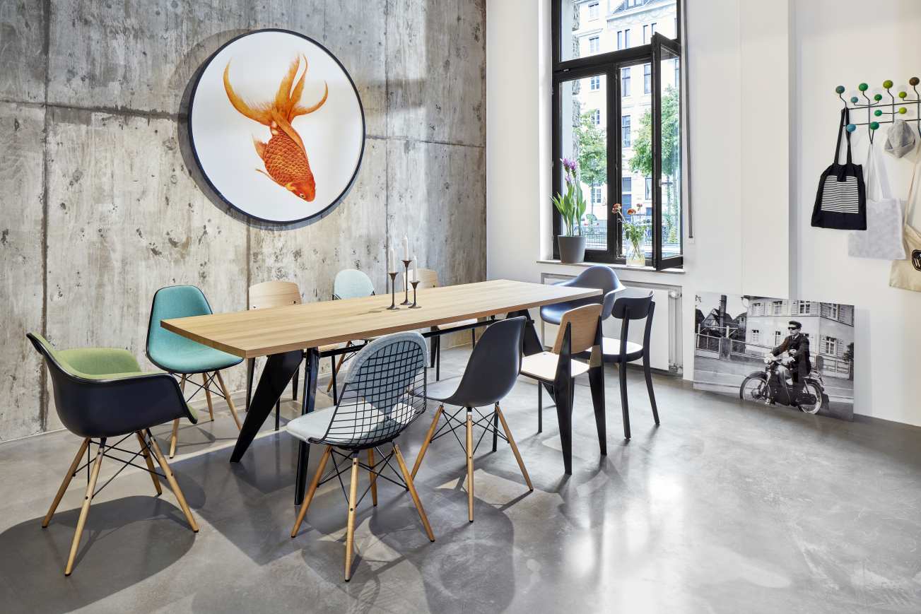 Vitra EM Table Holztisch mit Stühlen in modernem Esszimmer mit Betonwand und Fischbild.