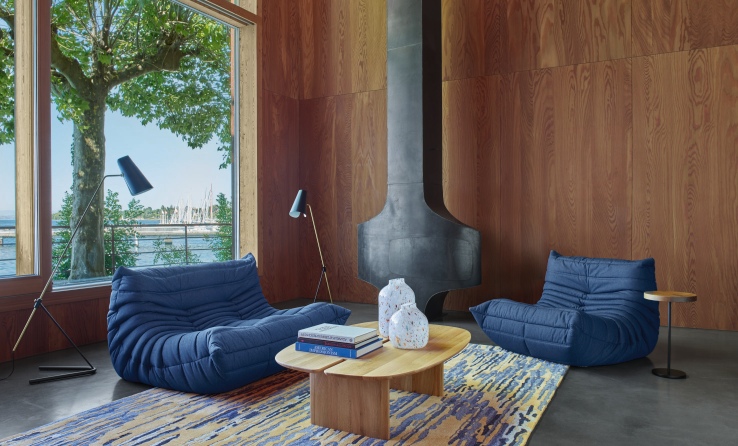 Blaues Togo Sofa von ligne roset in modernem Wohnzimmer mit Holzwand und Kamin.