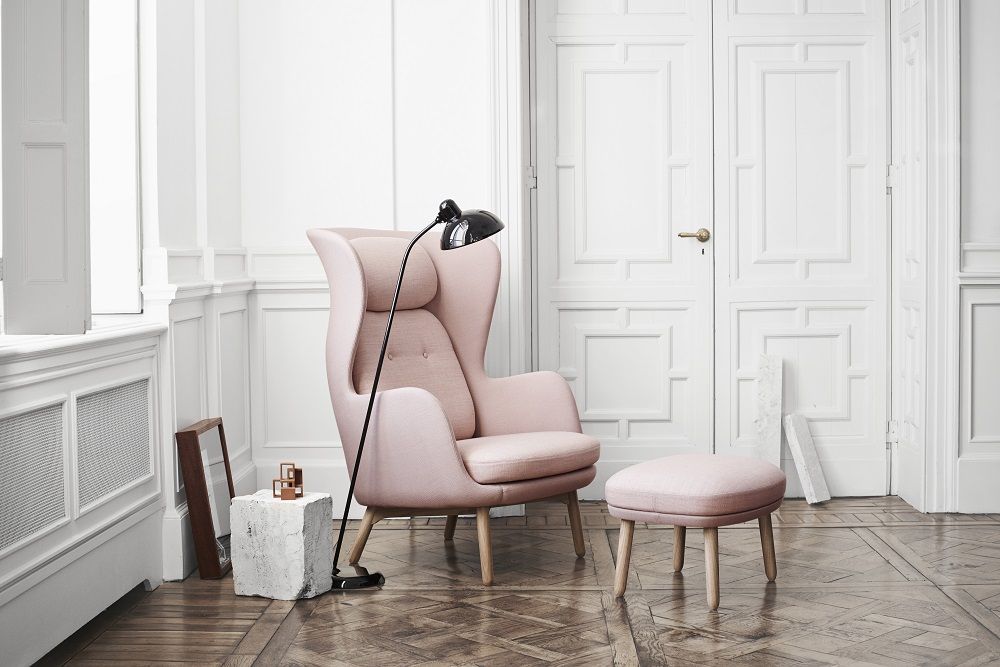 JH11 / JH12 Fußhocker für Ro Sessel von Fritz Hansen in Rosa vor weißer Wand.