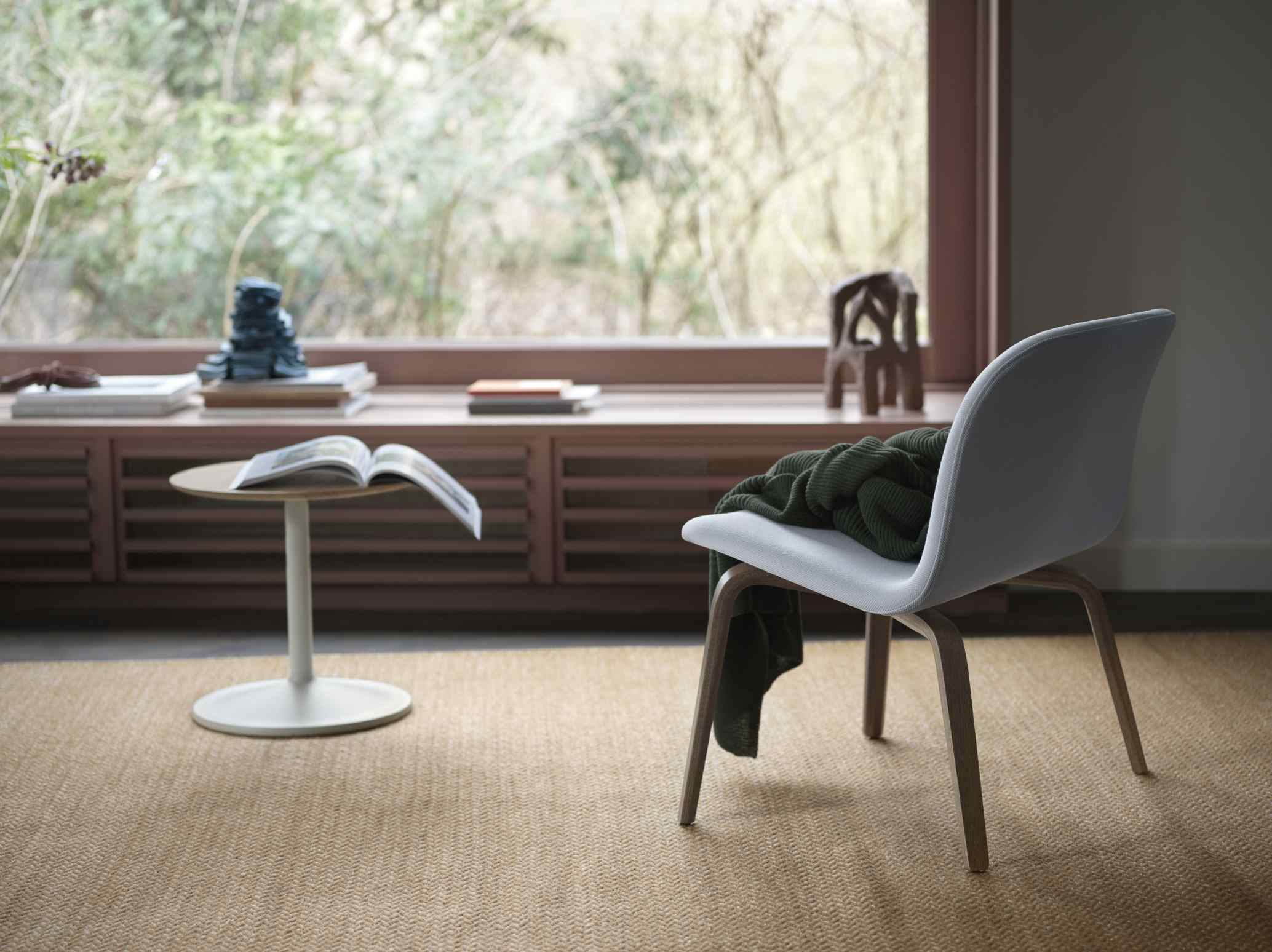 Nahaufnahme des Muuto Soft Side Table Beistelltisches mit Buch und Stuhl in wohnlicher Atmosphäre.