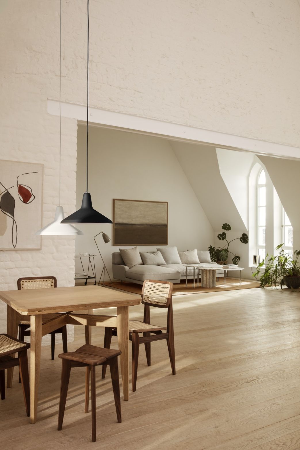 Heller Wohnraum mit Gubi B-Table Esstisch aus Holz und Stühlen mit Wiener Geflecht.