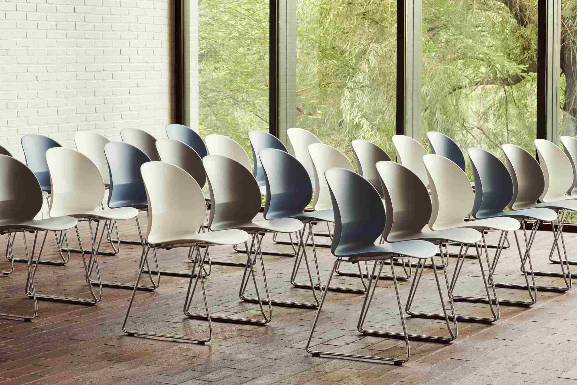 Reihe von Fritz Hansen N02 Recycle Stühlen in Grau- und Blautönen mit Stahlgestell vor Fenster.