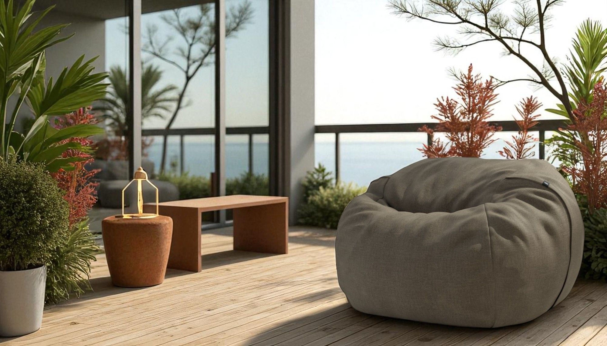 Vetsak Medium Outdoor Sitzsack in Grau auf einer Holzterrasse mit Meerblick und Dekoration.