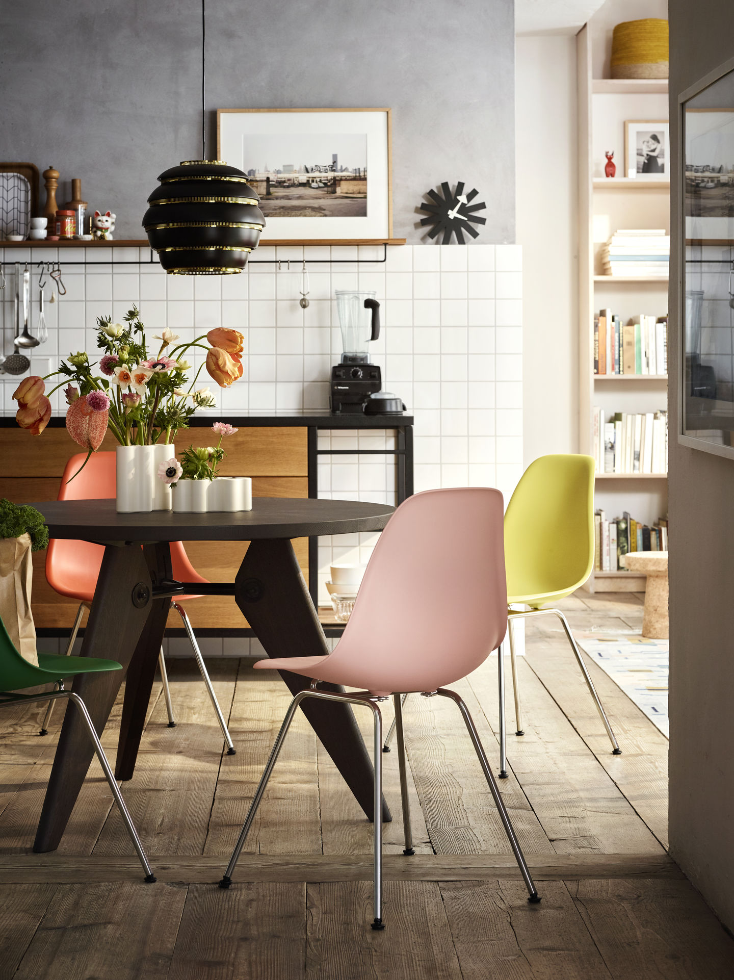 Eames Stühle in Rosa, Gelb, Grün und Orange um einen Esstisch in moderner Küche.