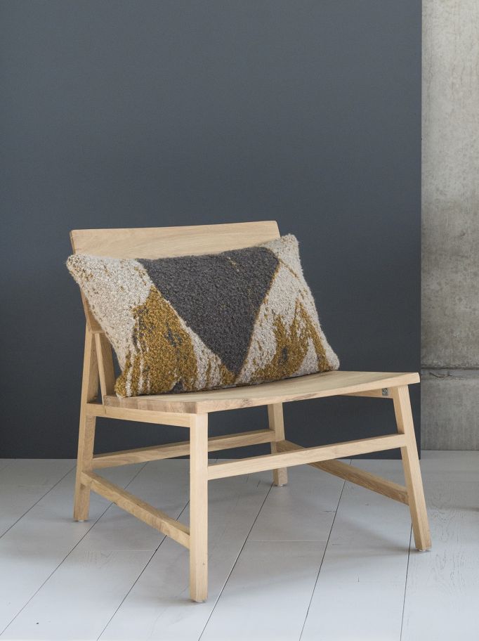 N2 Lounge Stuhl Eiche Ethnicraft mit gemustertem Kissen in Grau, Beige und Gelb auf hellem Holzboden.