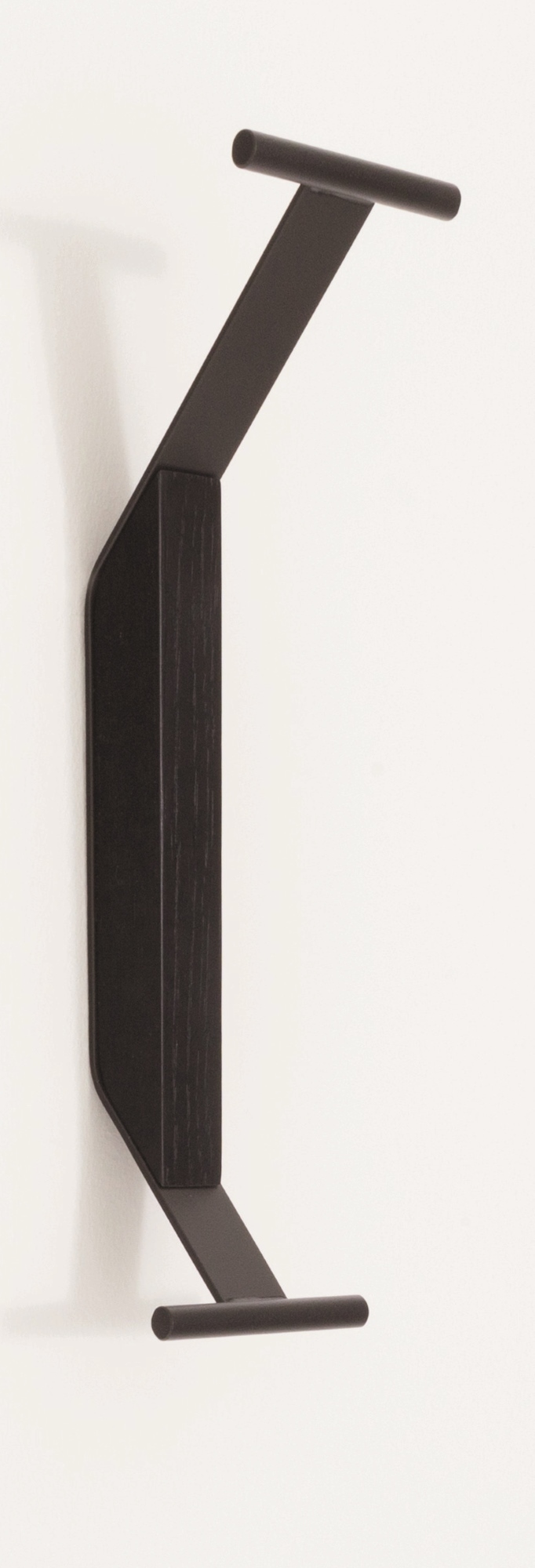 Schwarzer Artek Kaari Wandhaken REB 014 aus Holz und Metall an einer weißen Wand.