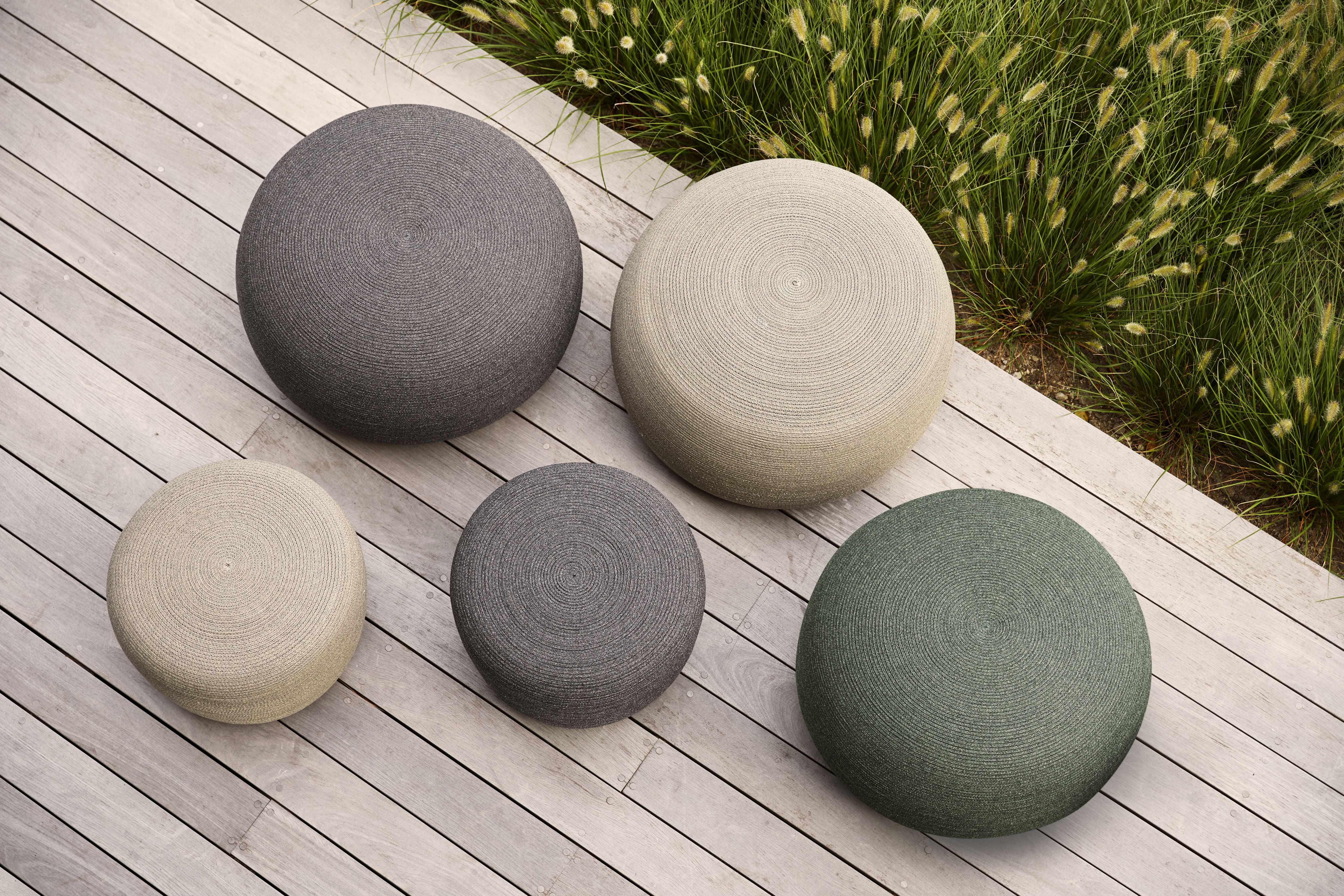 Circle Hocker von Cane-Line in verschiedenen Farben auf einer Holzterrasse, Gartenmöbel für den Außenbereich.