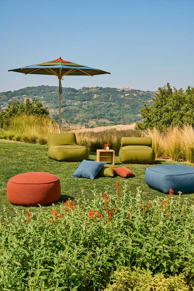 Weishäupl Sonnenschirm und Gartenmöbel auf Rasen mit Blick auf Hügellandschaft, ideal für entspannte Stunden im Freien.