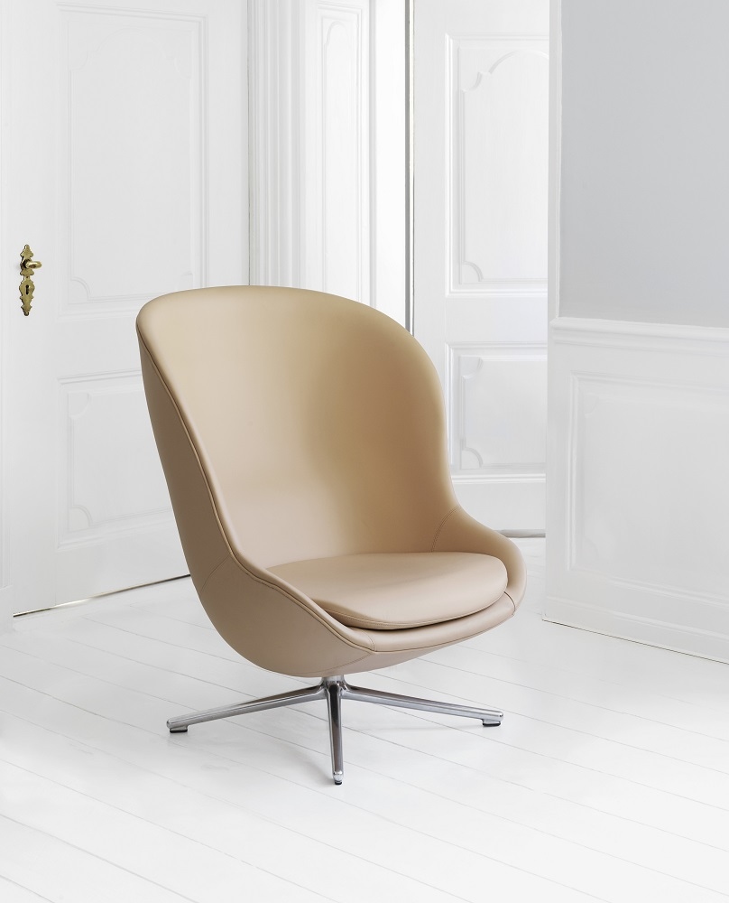 Beiger Hyg Lounge Sessel mit hohem Rücken und Drehgestell von Normann Copenhagen vor weißer Wand.