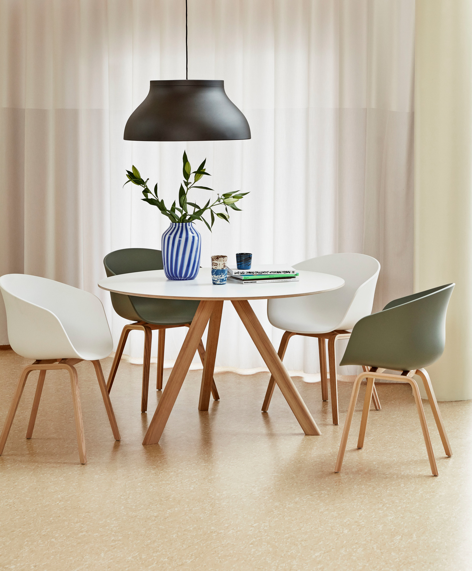 Heller Raum mit Copenhague Table CPH 20 Tisch rund von Hay, umgeben von vier Stühlen.