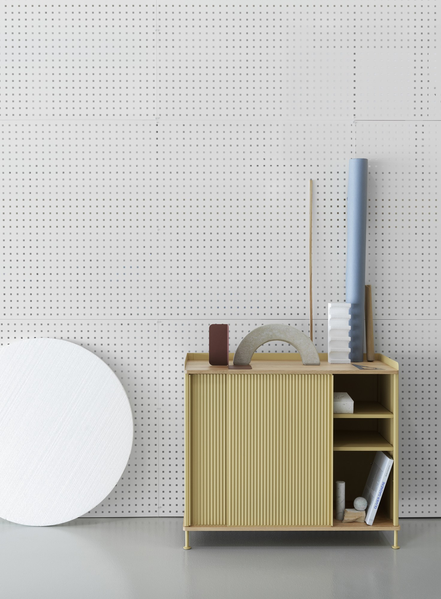 Gelbes Muuto Enfold Sideboard mit Schiebetür und Deko-Elementen vor gepunktetem Hintergrund. Modernes Design für Wohnzimmer und Esszimmer.
