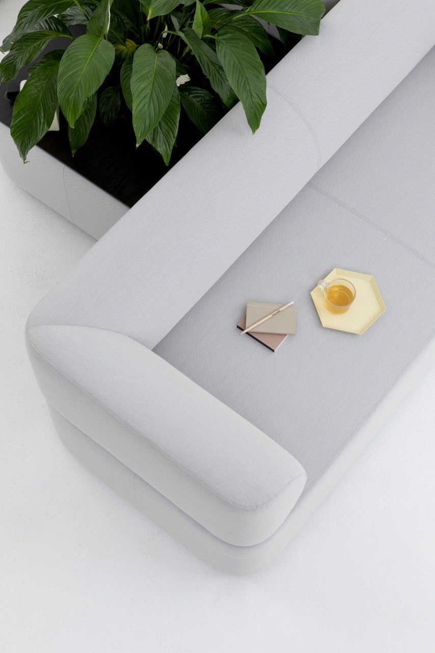 Helle Mezza Sofa Sitzelement von Cascando mit Pflanzkasten, Notizblock, Stift und Teetasse von oben.