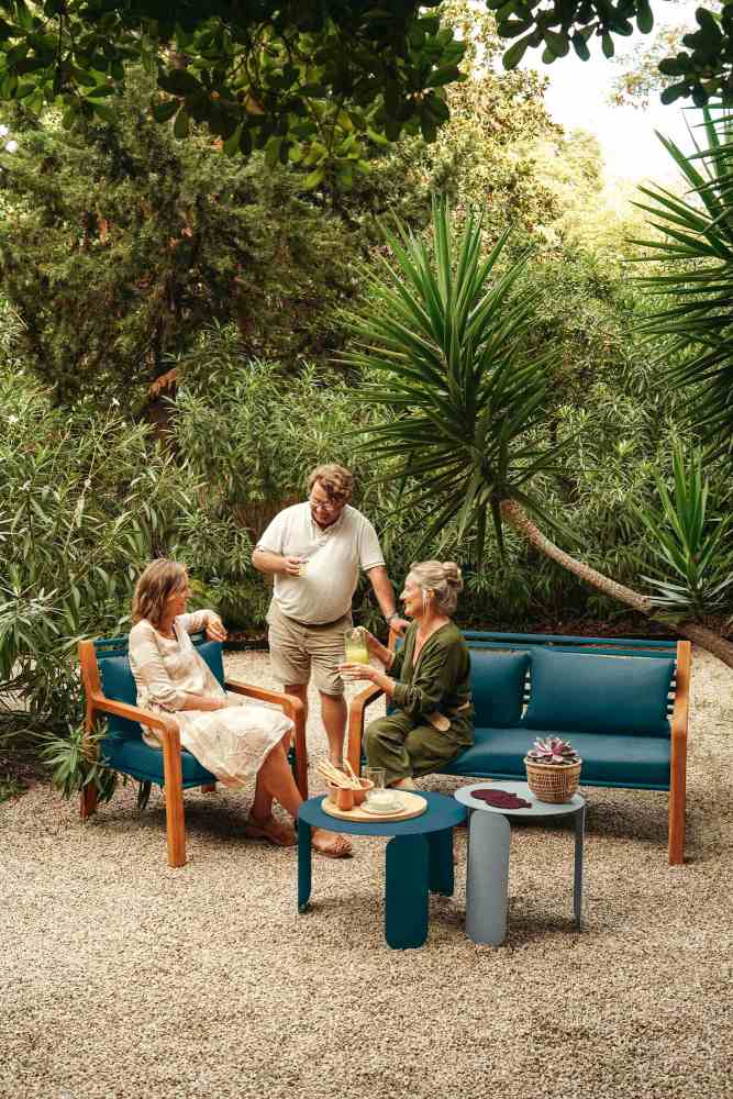 Somerset Sessel und Sofa von Fermob im Garten mit drei Personen beim Entspannen.