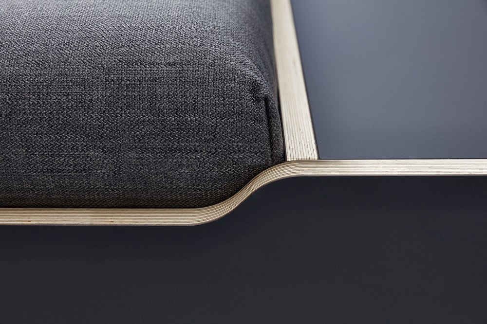 Detailaufnahme vom Maude Bett von Müller Möbelwerkstätten mit grauem Stoffbezug und blauem Nachttisch.