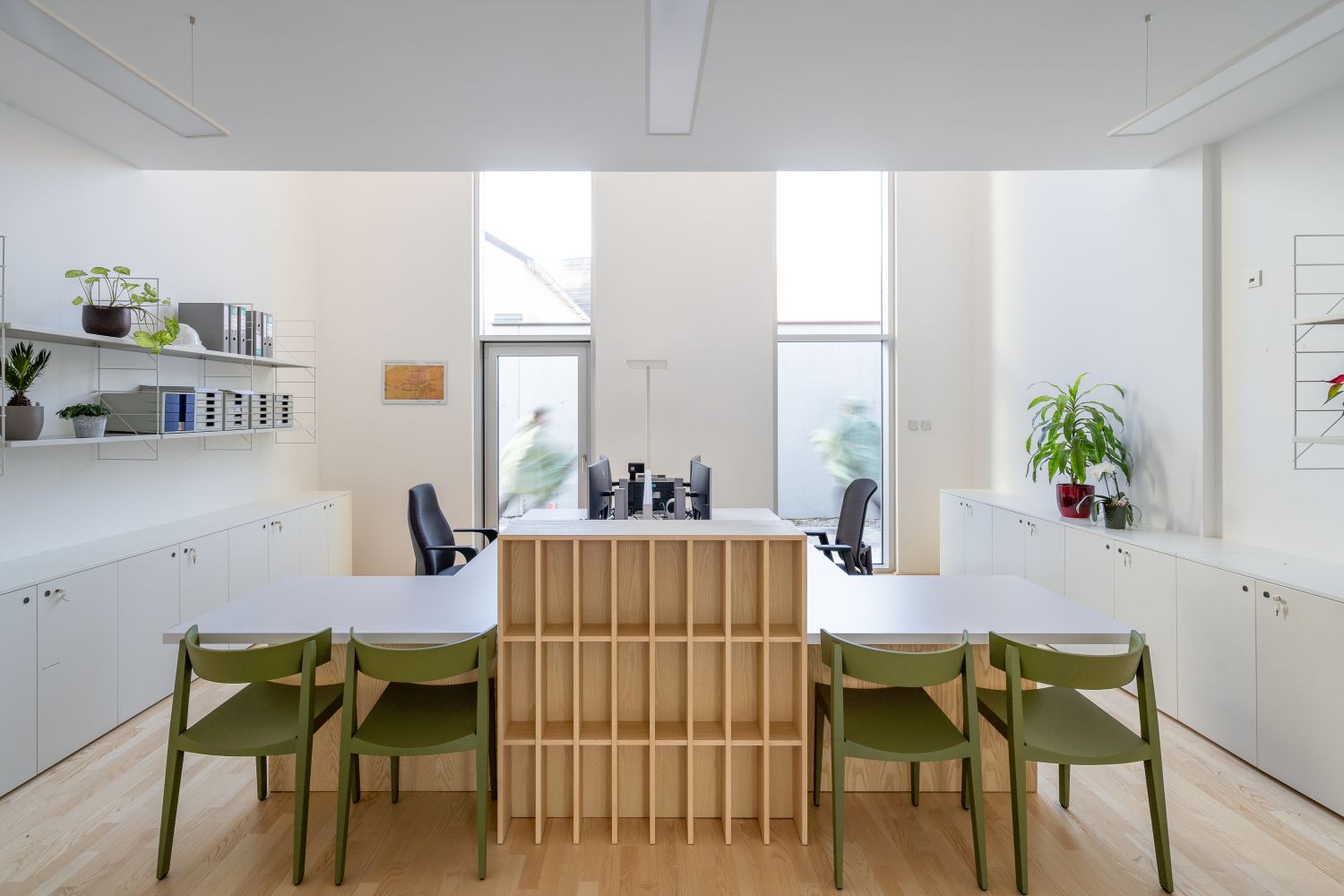Helles Büro mit grünen Bik Stühlen von Prostoria an weißen Schreibtischen und Regalen.