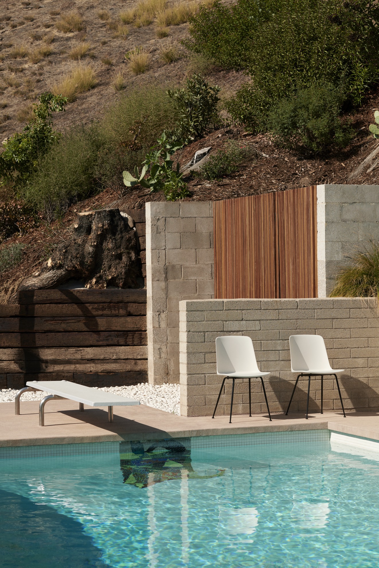 Zwei weiße Rely HW70 Outdoor Stühle von AndTradition stehen am Pool, modernes Gartenmöbel Design.