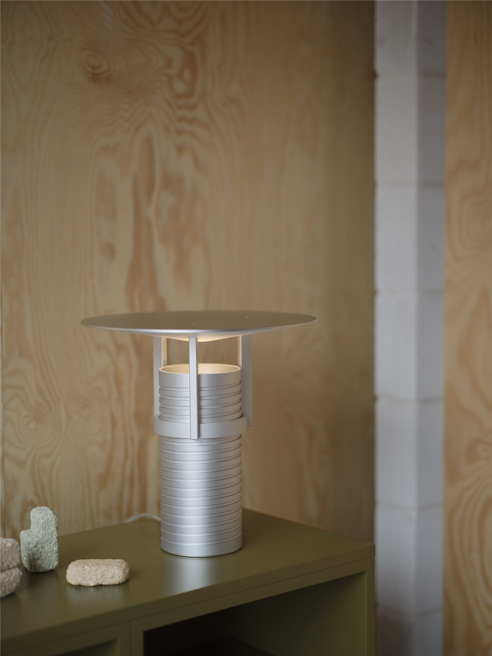 Nahaufnahme der Muuto Set Table Lamp Tischleuchte in Silber auf einem grünen Nachttisch.
