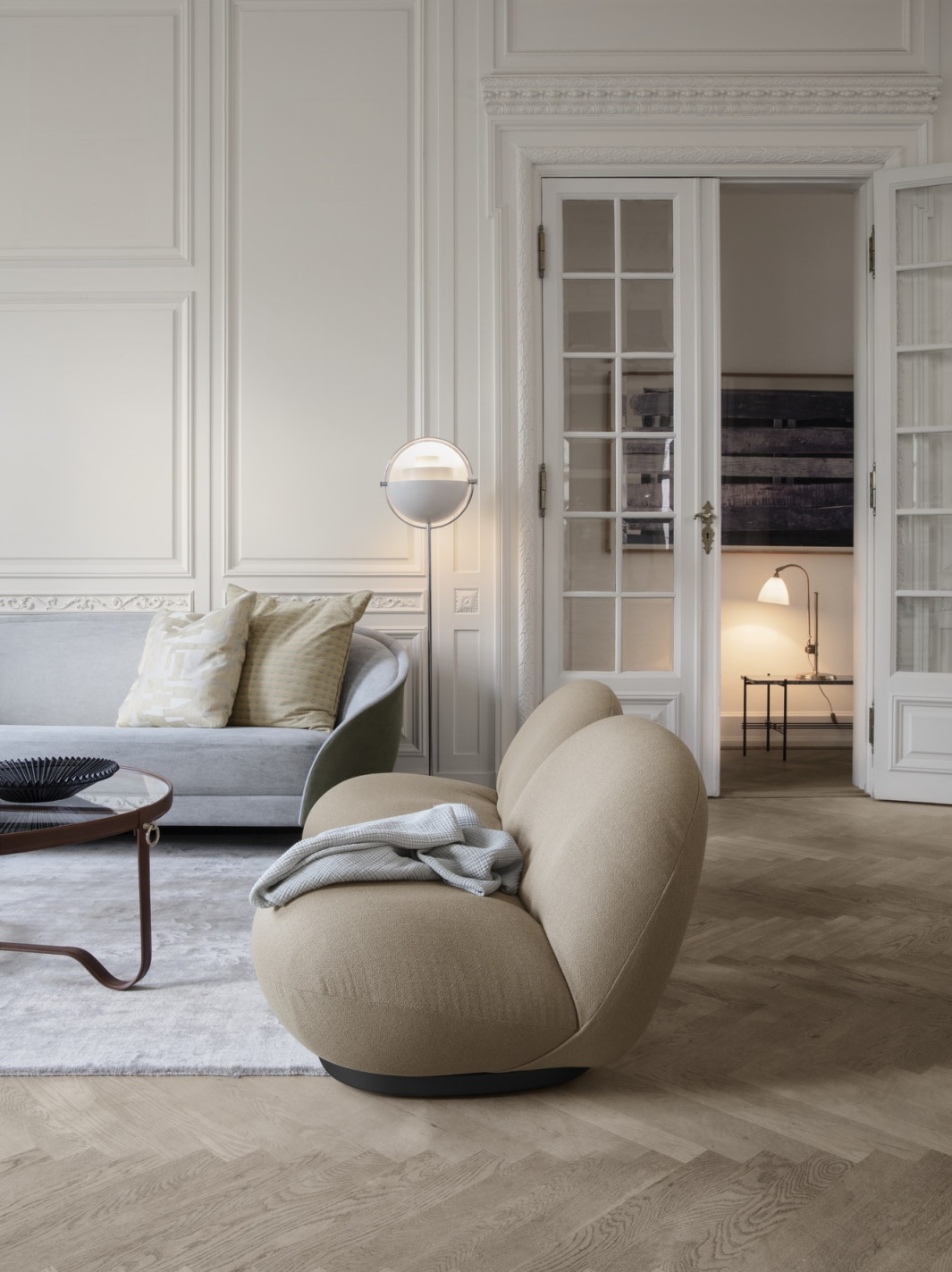 Wohnzimmer mit Adnet Coffee Table Couchtisch von Gubi, Sofa, Sessel und Holzboden.