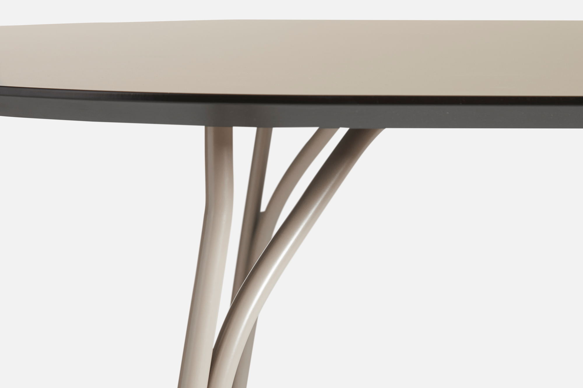 Detailaufnahme des Tree Esstischs von Woud: Beige Tischplatte mit dunklem Rand und geschwungenen Beinen.