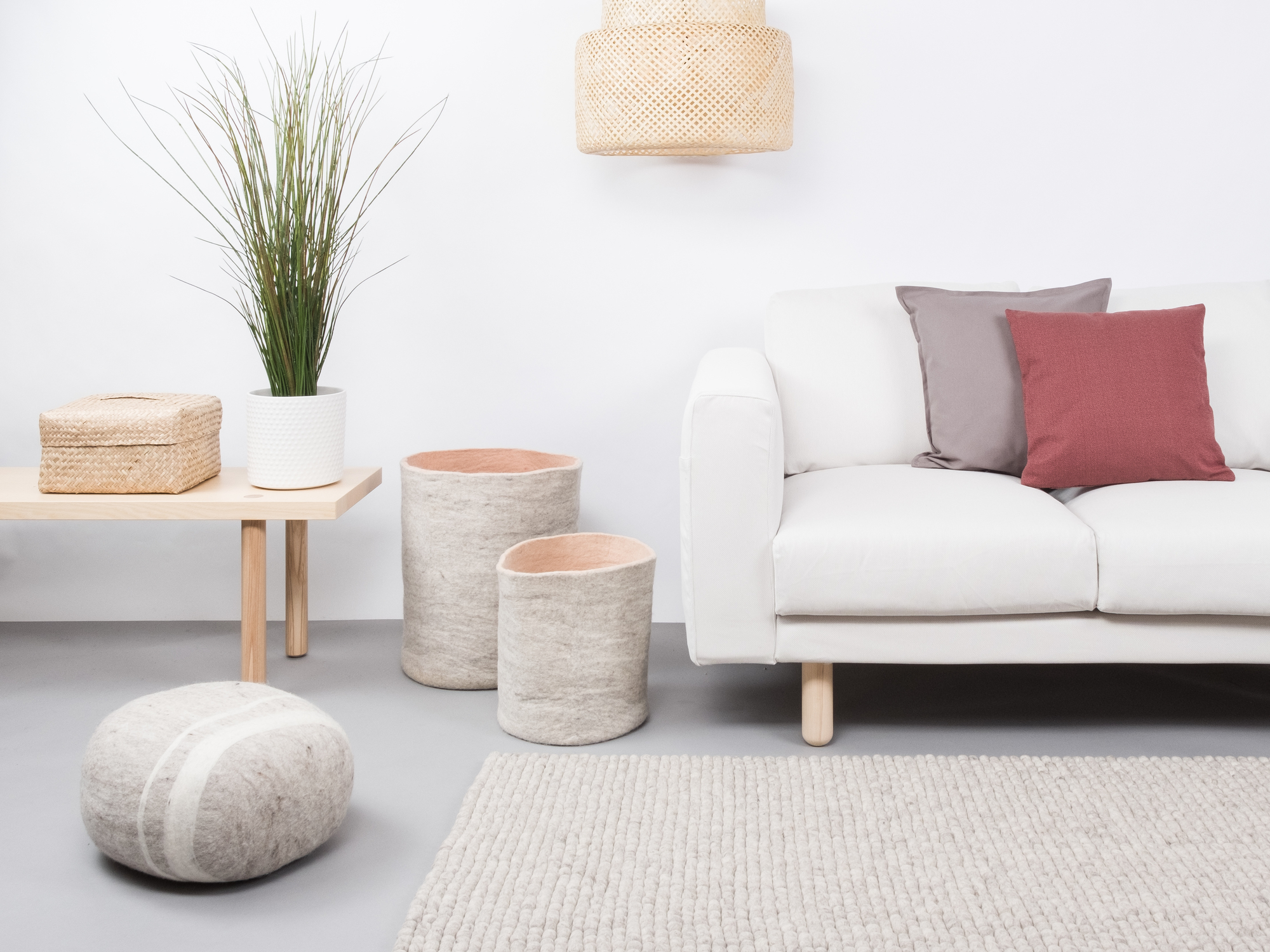 Heller Wohnraum mit Sofa und myfelt Filzkugel Teppich 140x200 cm in Beige.