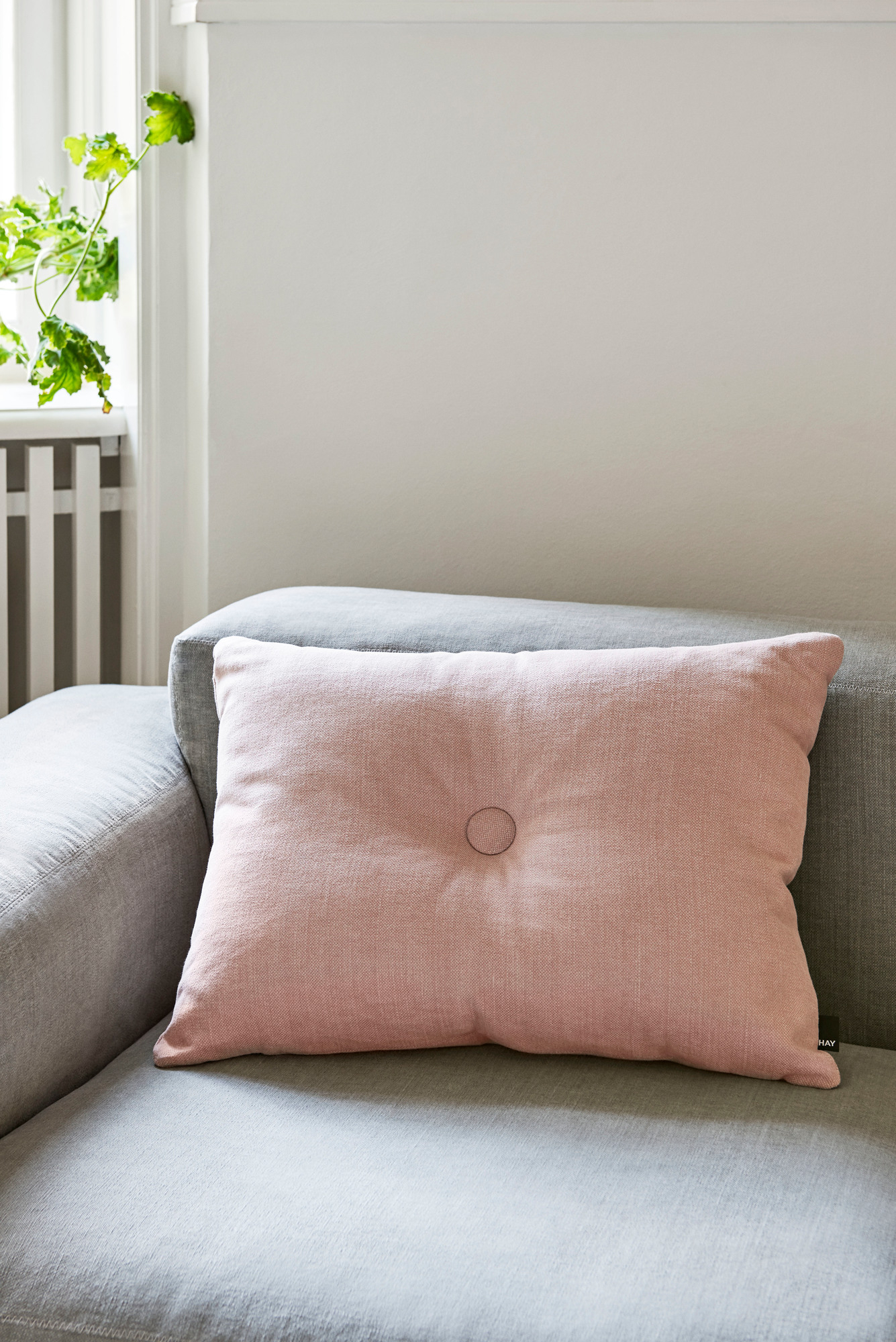 Nahaufnahme des Hay Mags Soft Sofa mit rosa Zierkissen auf grauem Stoffbezug.