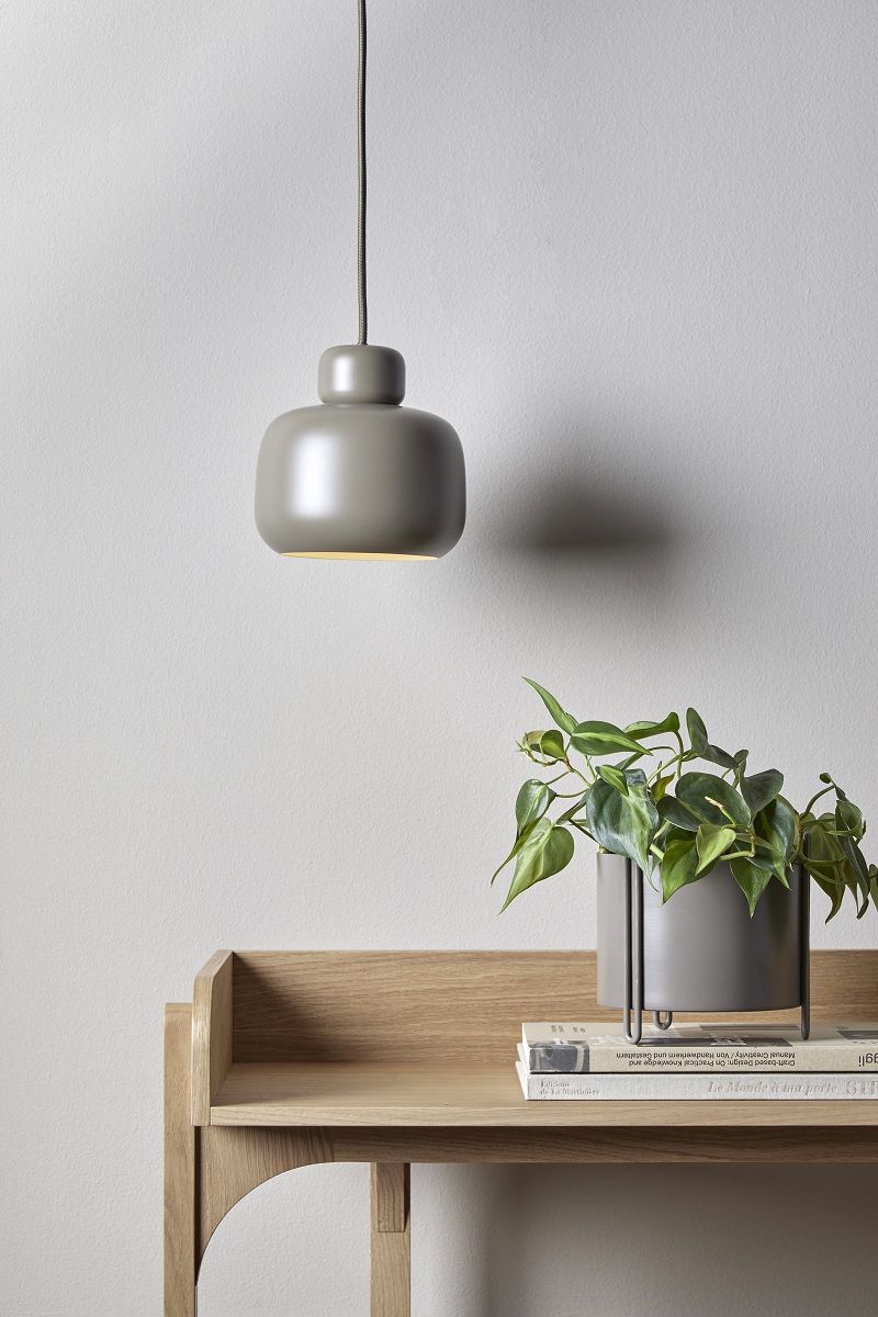 Graue Woud Pendelleuchte über einem hellen Holzregal mit Pflanze und Büchern, minimalistisches skandinavisches Design.