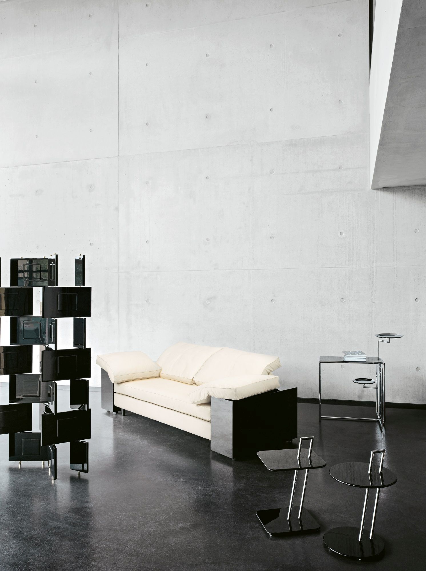 Beige Lota Sofa von Classicon mit schwarzen Akzenten in modernem Interieur mit Betonwand und Designermöbeln.