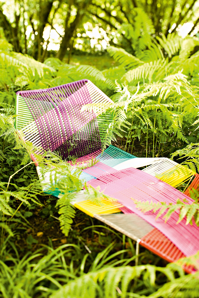 Moroso Tropicalia Outdoor Liege im Garten, bunte Designer Gartenliege aus geflochtenem Kunststoff zwischen Farnen.