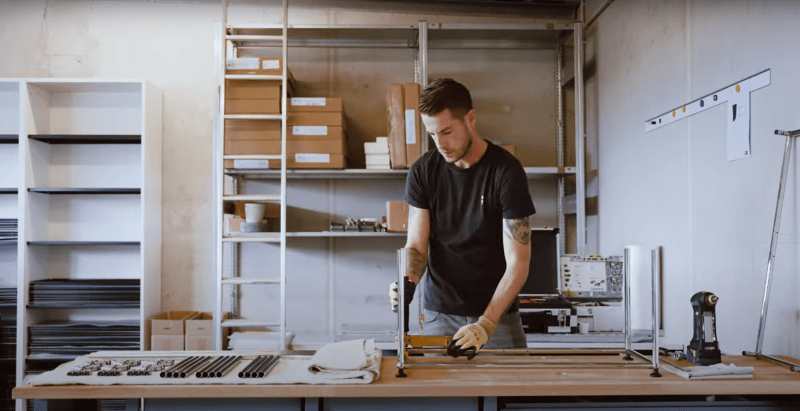 Montage-Experte von einrichten design montiert USM Haller Metallrohre für ein Produkt, Werkzeuge und Regale im Hintergrund.