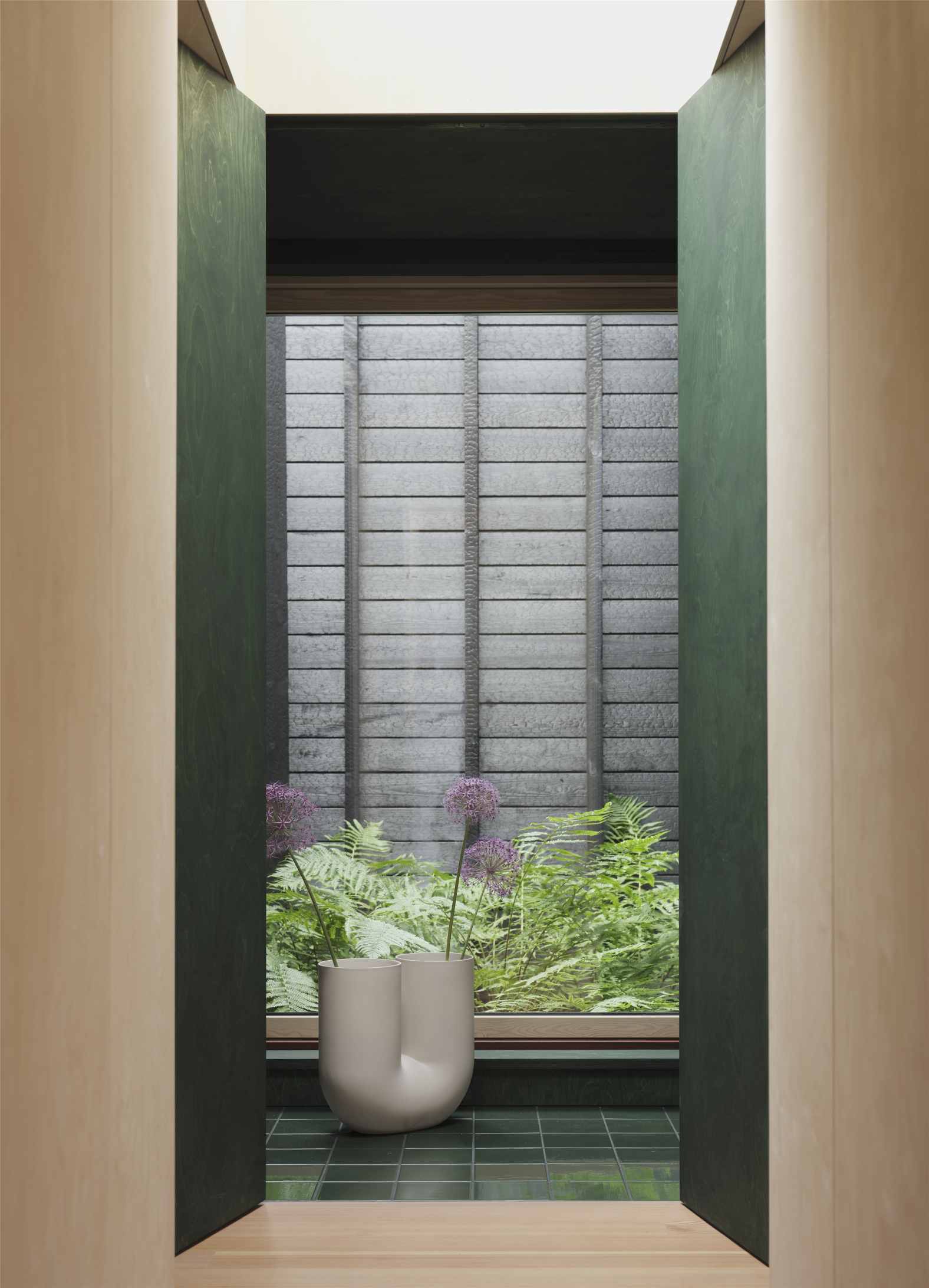 Helle Muuto Kink Vase mit Blumen vor Fenster und grünen Fliesen, modernes Wohndesign.
