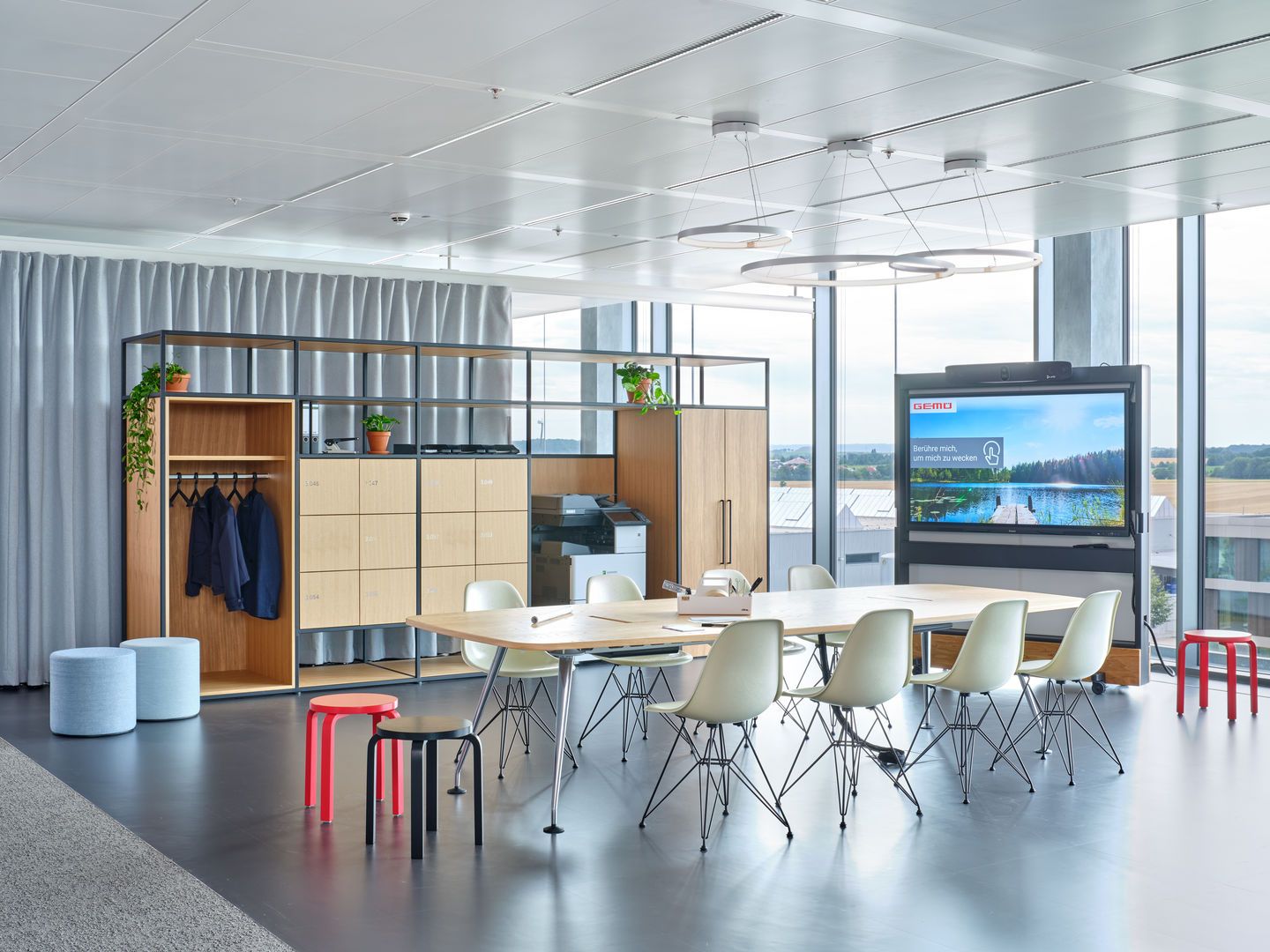 Besprechungsraum mit mehreren weißen Eames DSR Stühlen mit Sitzpolster von Vitra um einen Tisch.